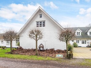 Een wit gebouw met een puntgevel, een klein portaaltje en een bank.