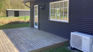A single-story building with a wooden deck, a large window, and an air conditioning unit. - 5 Star Holiday Home in Ansager (Ansager)