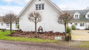 A white building with a triangular roof, a small window, and a welcome sign. - 5 Star Holiday Home in Ansager (Ansager)