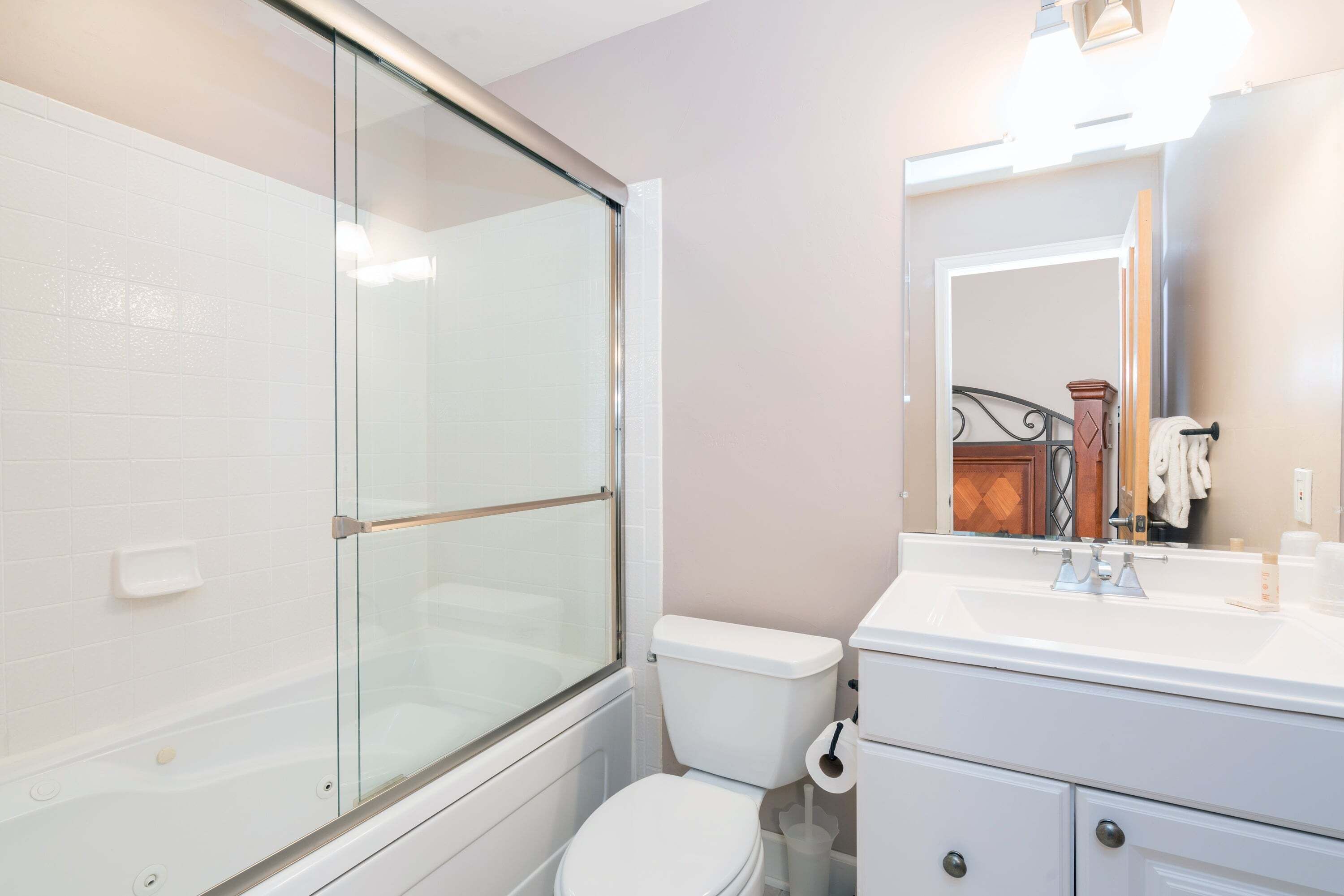 A bathroom with a glass-enclosed shower, a white toilet, and a sink with a mirror above it.