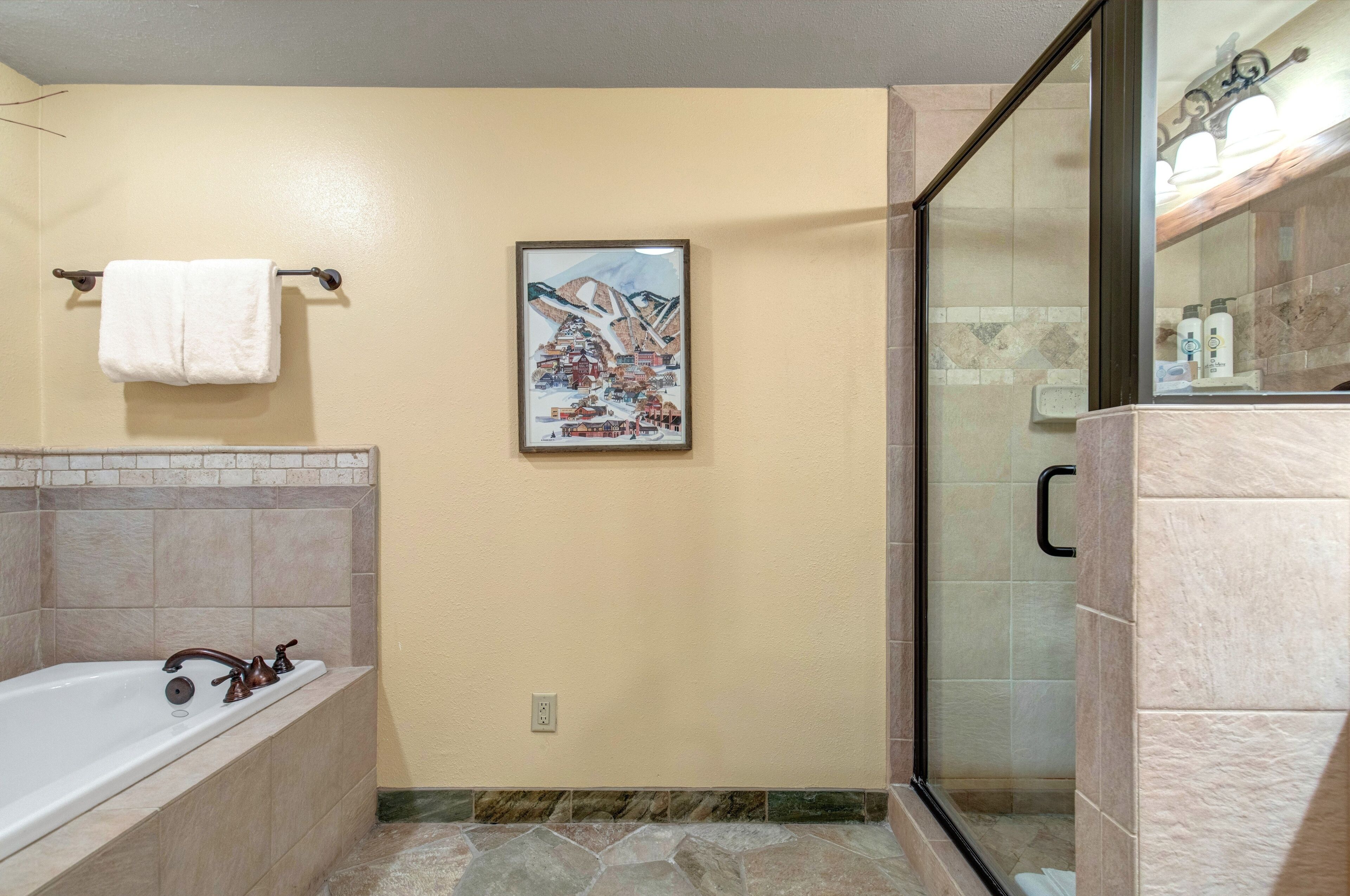 Un baño con bañera, cabina de ducha de vidrio y un cuadro enmarcado en la pared.