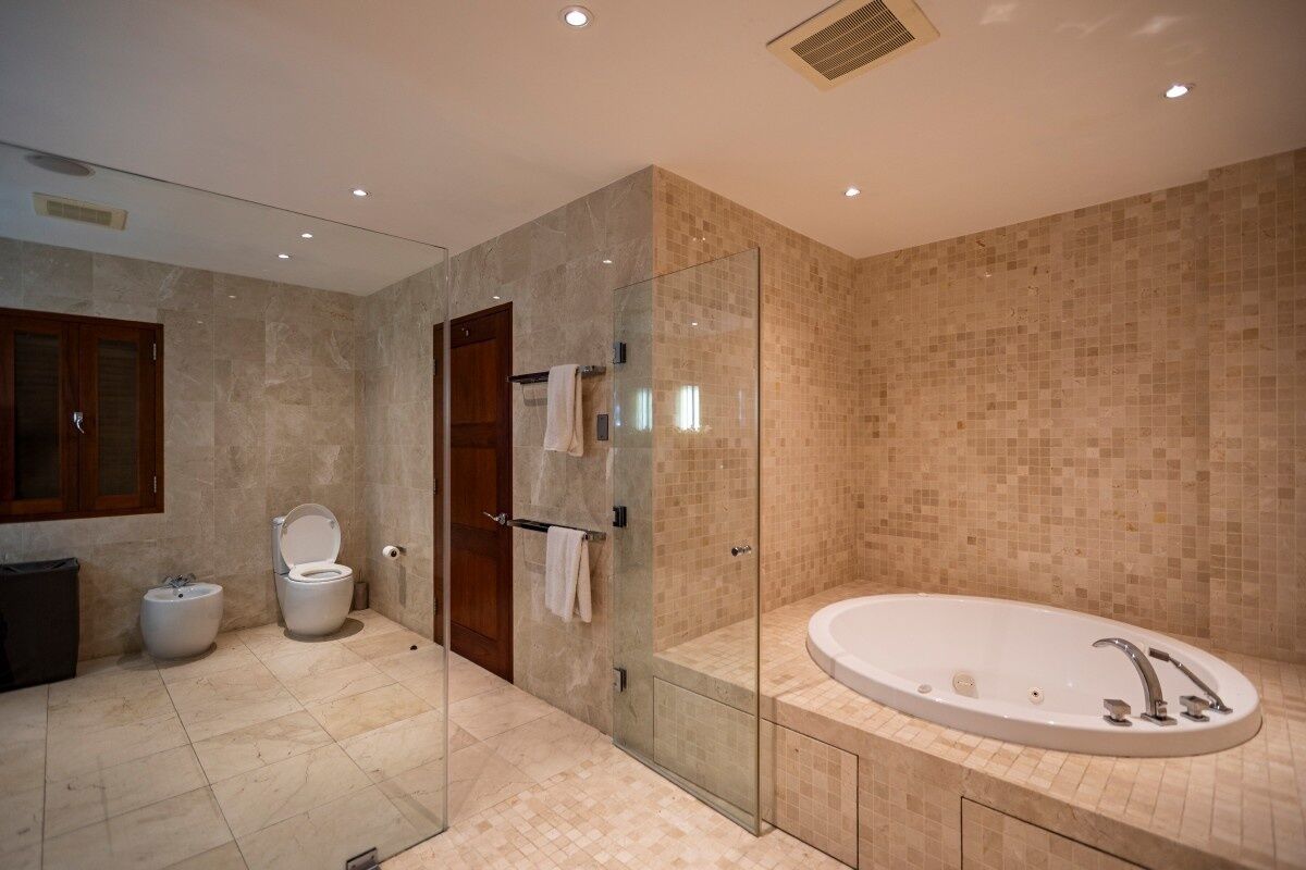 A modern bathroom with a glass-enclosed shower, a freestanding bathtub, and a toilet.