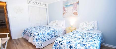 A bedroom with two beds, a star map on the wall, and a painting of a beach scene.