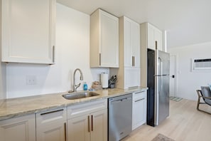 Una cucina moderna con mobili bianchi, elettrodomestici in acciaio inossidabile e lavastoviglie integrata.