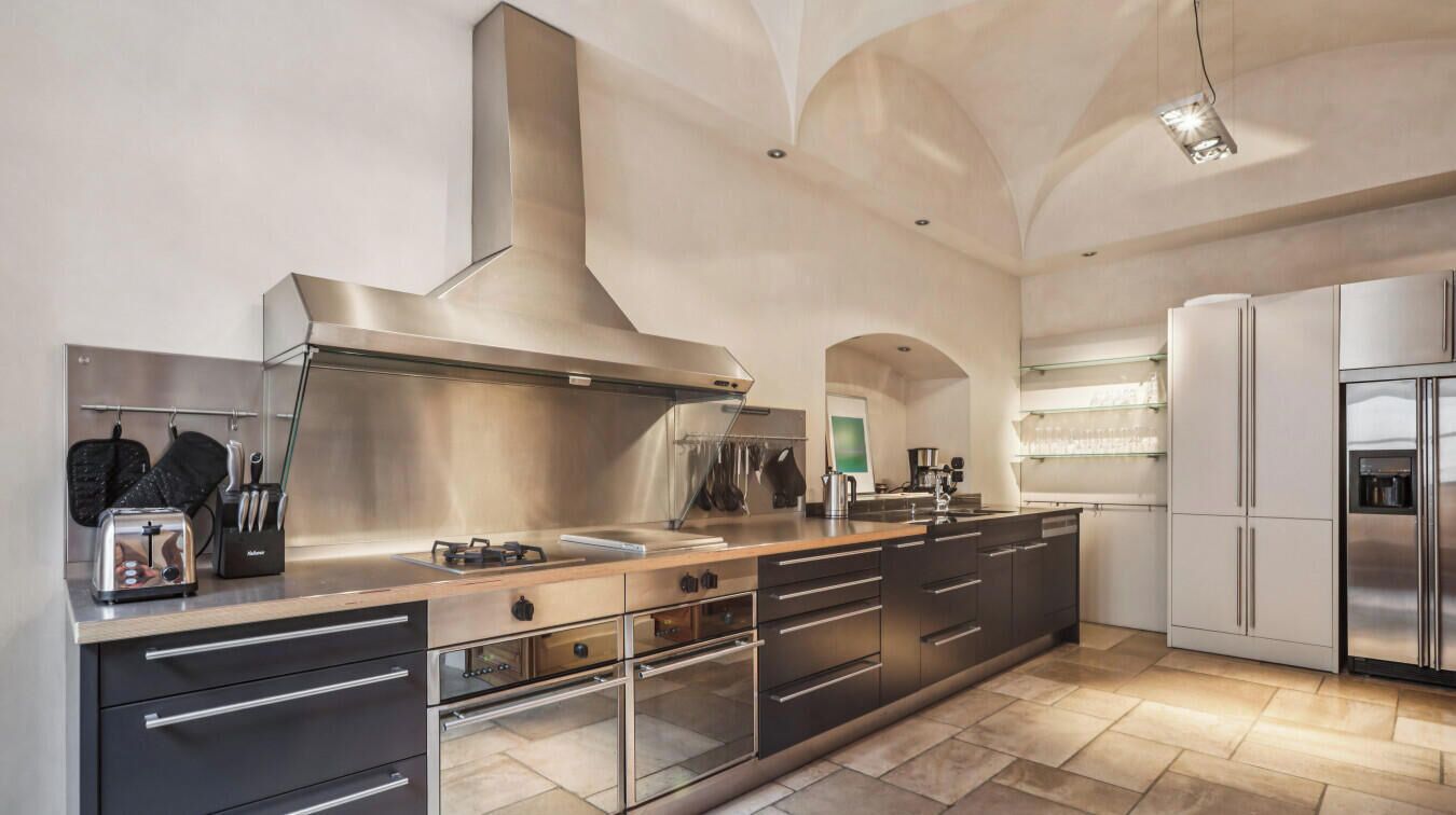 Een moderne keuken met roestvrijstalen apparatuur, een groot schiereiland en een hoge plafond met een boogvormig ontwerp.