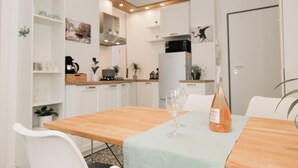 A modern kitchen with white cabinets, a wooden table, and a wine bottle. - Centro-Brera, MM2 Moscova-Garibaldi, Corso Como. (Milano)