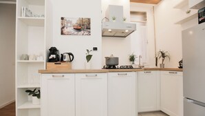 A modern kitchen with white cabinetry, a gas stove, and a built-in oven. There are potted plants on the countertops and a coffee machine on the counter. - Centro-Brera, MM2 Moscova-Garibaldi, Corso Como. (Milano)