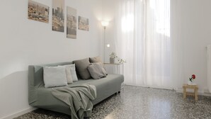 A modern living room with a grey sofa, a small wooden side table, and a floor lamp. - Centro-Brera, MM2 Moscova-Garibaldi, Corso Como. (Milano)
