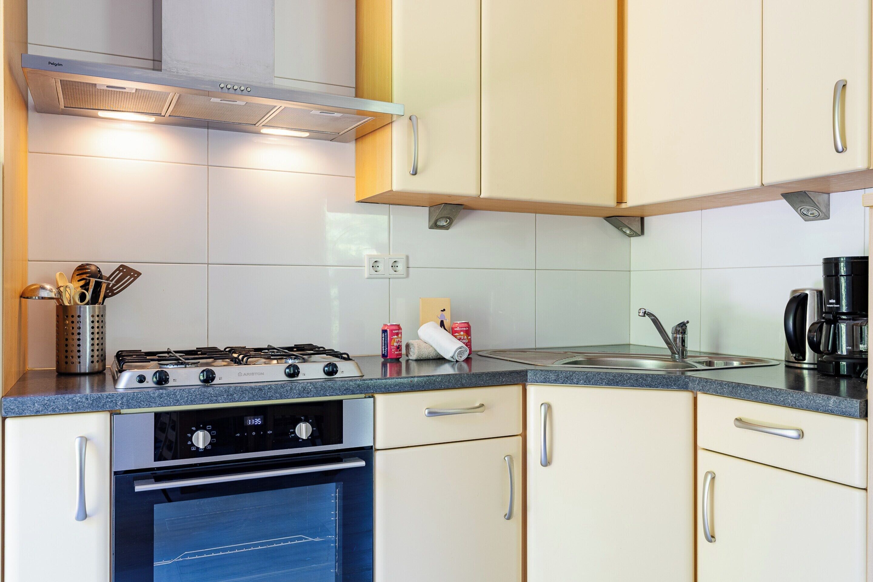 Una cocina con estufa a gas, horno y cafetera.