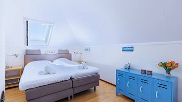 A bedroom with a bed, a blue wardrobe, a nightstand, and a window.