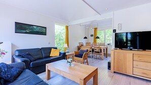 A modern living room with a sofa, coffee table, and dining area. - Westduin Apartment Near the Beach (Vlissingen)