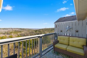 A balcony with a wicker sofa and decorative wall elements. - Ozark Viewpoint Retreat for 8 (Branson)