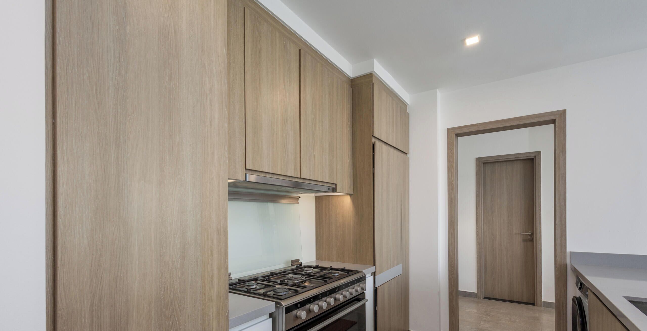 Une cuisine avec des meubles de rangement en bois, une cuisinière et un four.