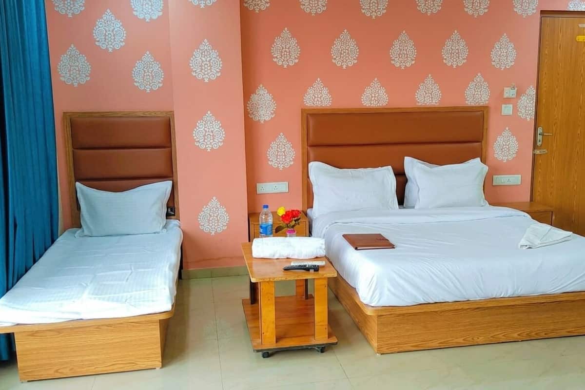 Une chambre double avec deux lits simples, une table de chevet en bois, une petite table avec une télécommande et une porte avec une pancarte.