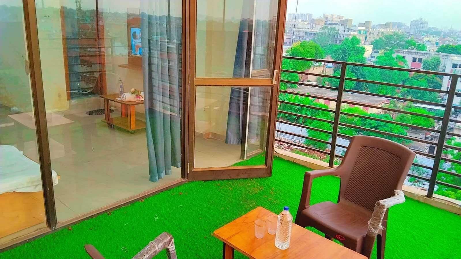 Ein Balkon mit künstlichem Rasen, einem Tisch mit Flasche und Glas sowie einem Stuhl.