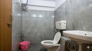 A bathroom with a toilet, sink, and shower. - Hotel Sun Stay Ahmedabad (Ahmedabad)