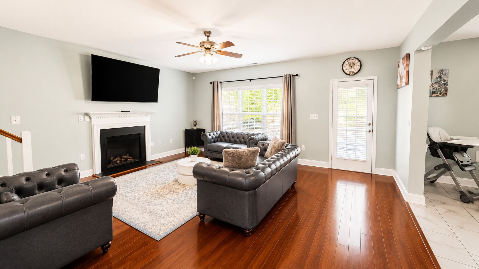A living room with a fireplace, a television, and a ceiling fan.