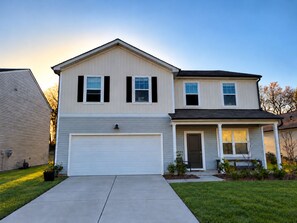 A two-story residential house with a garage, a front porch, and a well-maintained lawn. - Designer Luxury Near Downtown Concord/Charlotte, NASCAR, and Renaissance Fair (Concord)