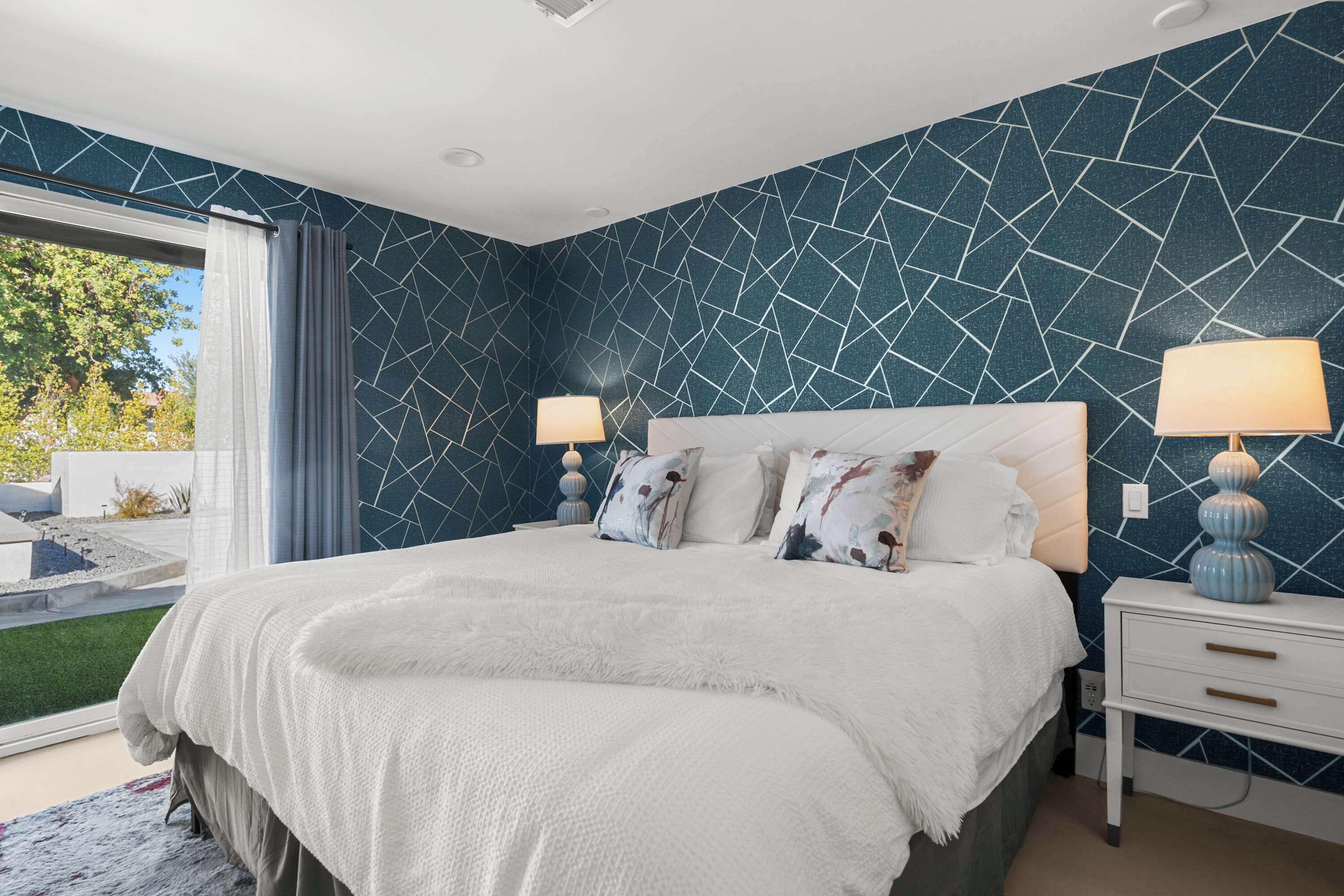 Een slaapkamer met een groot bed, twee nachtkastjes en uitzicht op de omgeving.