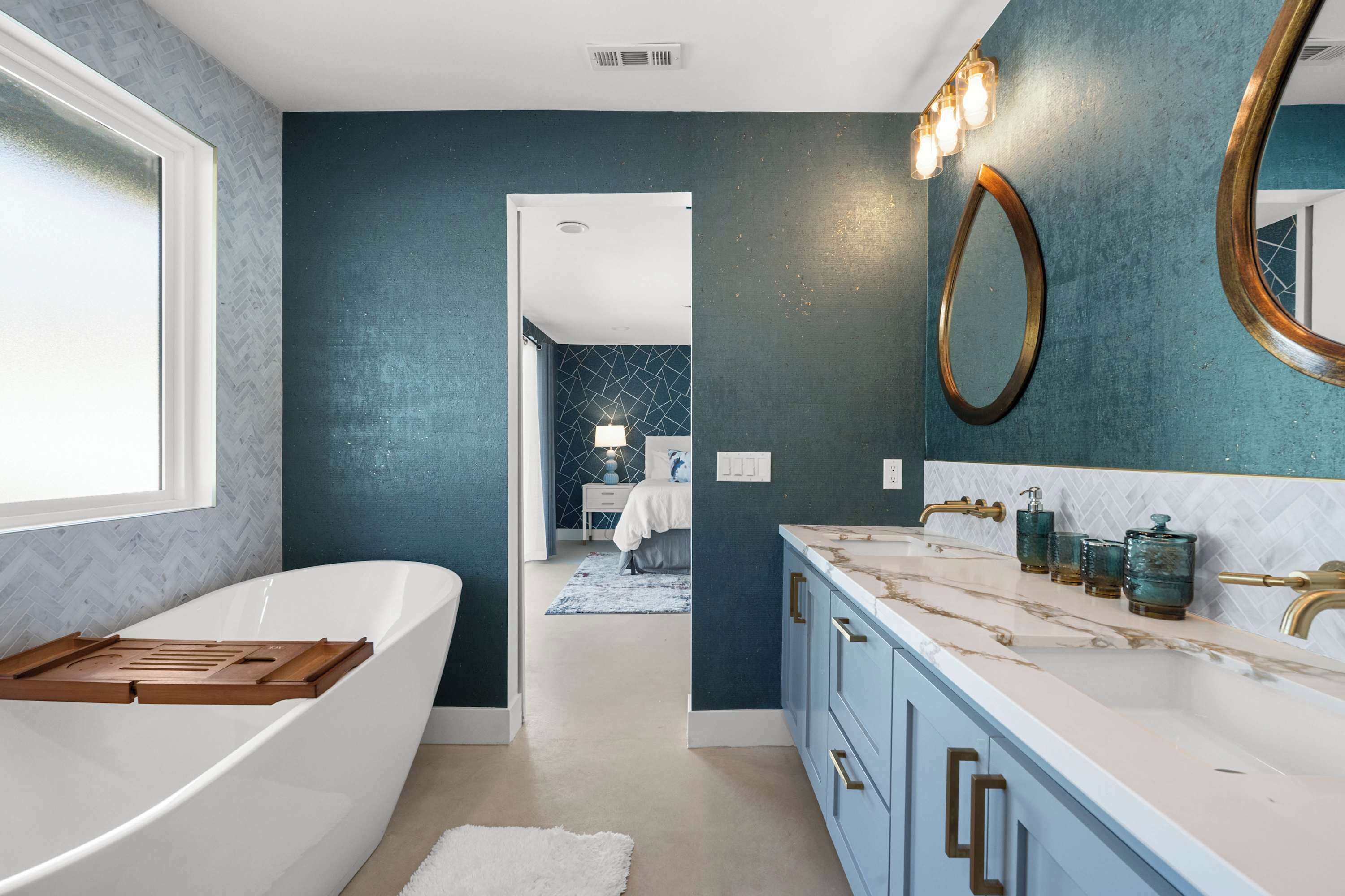 A modern bathroom with a freestanding bathtub, a vanity with a marble countertop, and a large mirror.
