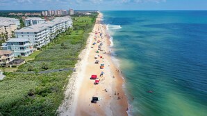 Una playa con una hilera de edificios, algunos con balcones, y una vista despejada del océano.