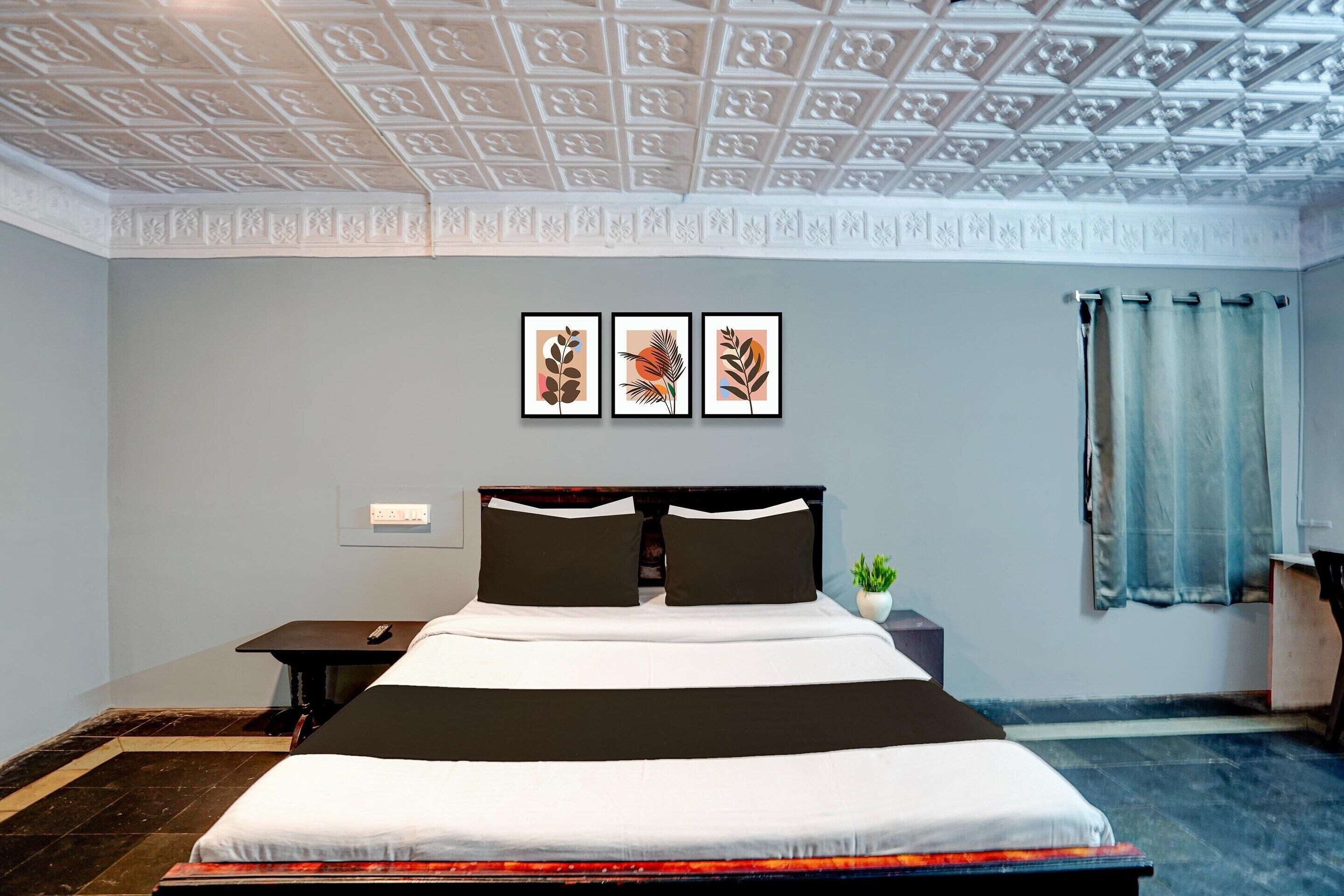 A bedroom with a bed, a nightstand, a wall-mounted TV, and framed artwork.