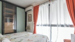 Une chambre à coucher avec un lit, une chaise et une fenêtre avec des rideaux.