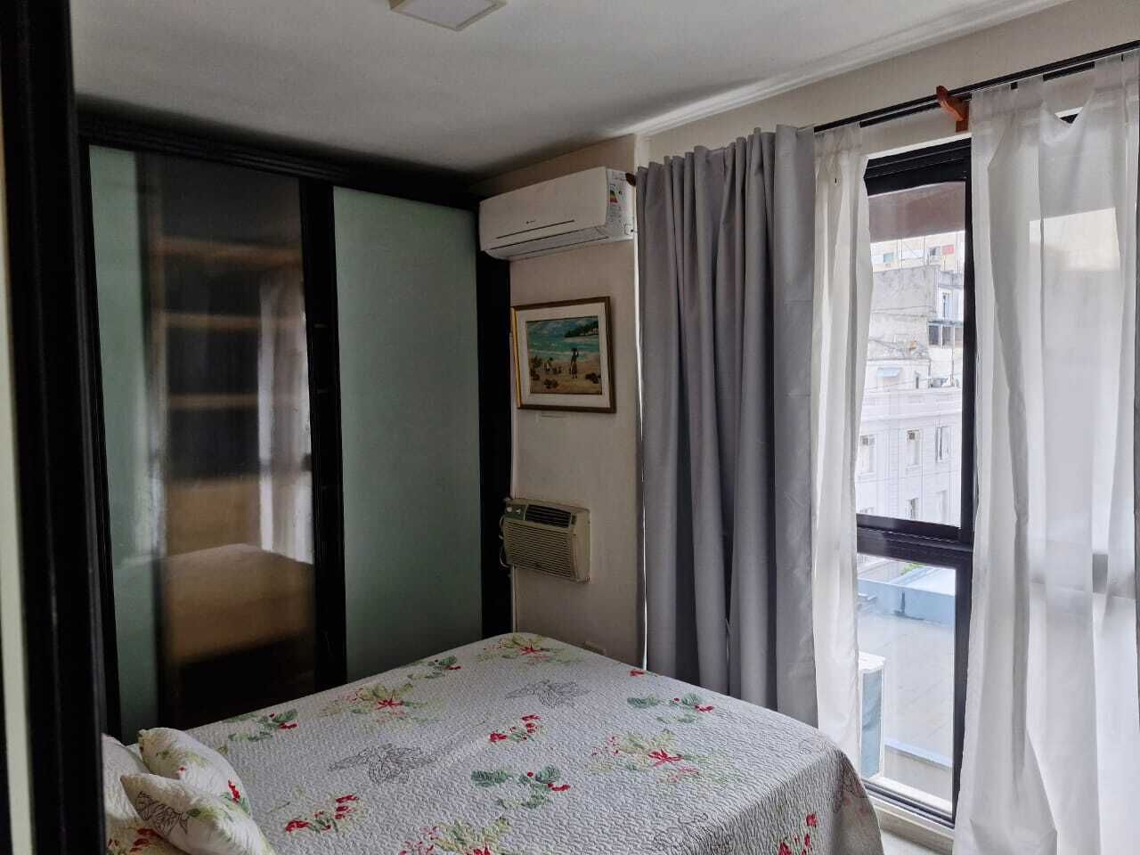 Een kamer met een bed, een raam met gordijnen, een airconditioning en een foto aan de muur.