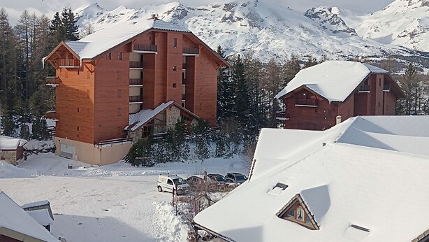 A wooden chalet with a balcony, surrounded by snow-covered mountains. - 4/6-person apartment, 5 floors with elevator (Dévoluy)