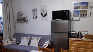 A compact living space with a bed, a refrigerator, a microwave, a table with chairs, and a small kitchen area. - 4/6-person apartment, 5 floors with elevator (Dévoluy)