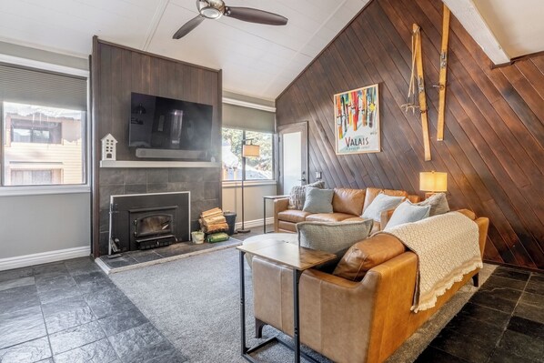 Una sala de estar acogedora con chimenea, un sofá, una mesa de centro y un televisor.