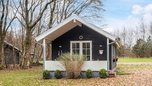 A small, single-story house with a white porch, a black exterior, and a white door. - 5 Star Holiday Home in Ansager (Ansager)