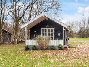 A small, single-story house with a white porch, a black exterior, and a white door. - 5 Star Holiday Home in Ansager (Ansager)