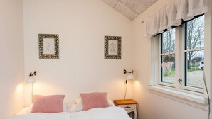 A bedroom with a bed, two bedside lamps, a nightstand, and two wall-mounted picture frames. - 5 Star Holiday Home in Ansager (Ansager)
