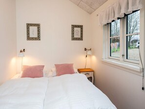 A bedroom with a bed, two bedside lamps, a nightstand, and two wall-mounted picture frames. - 5 Star Holiday Home in Ansager (Ansager)