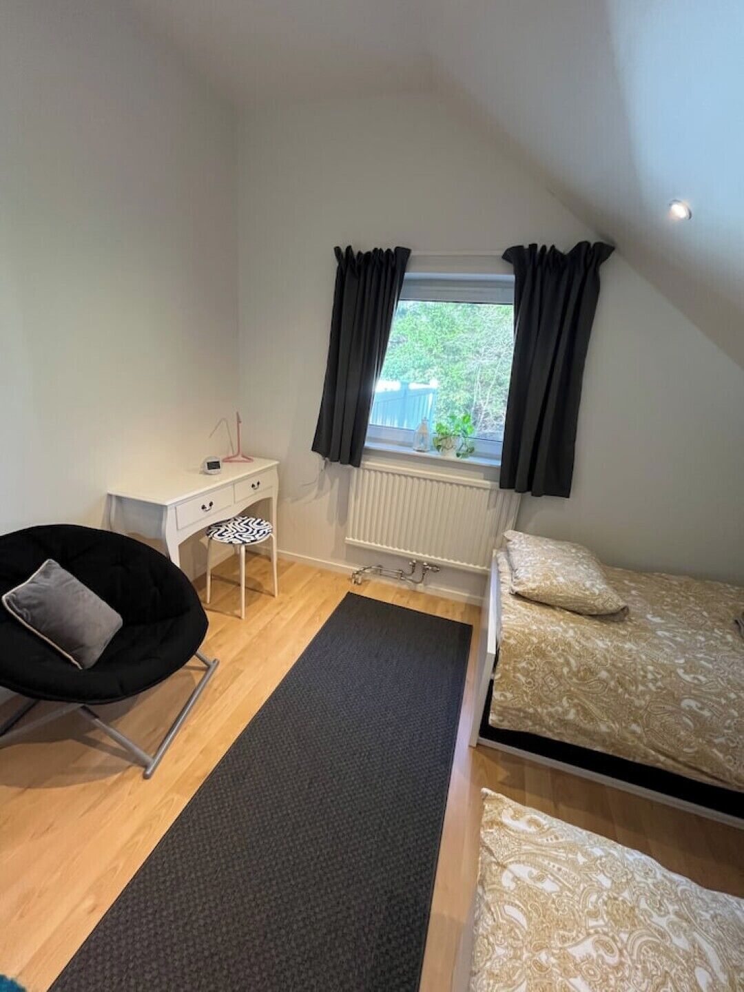 Un dormitorio con cama, escritorio, silla y ventana con cortinas.