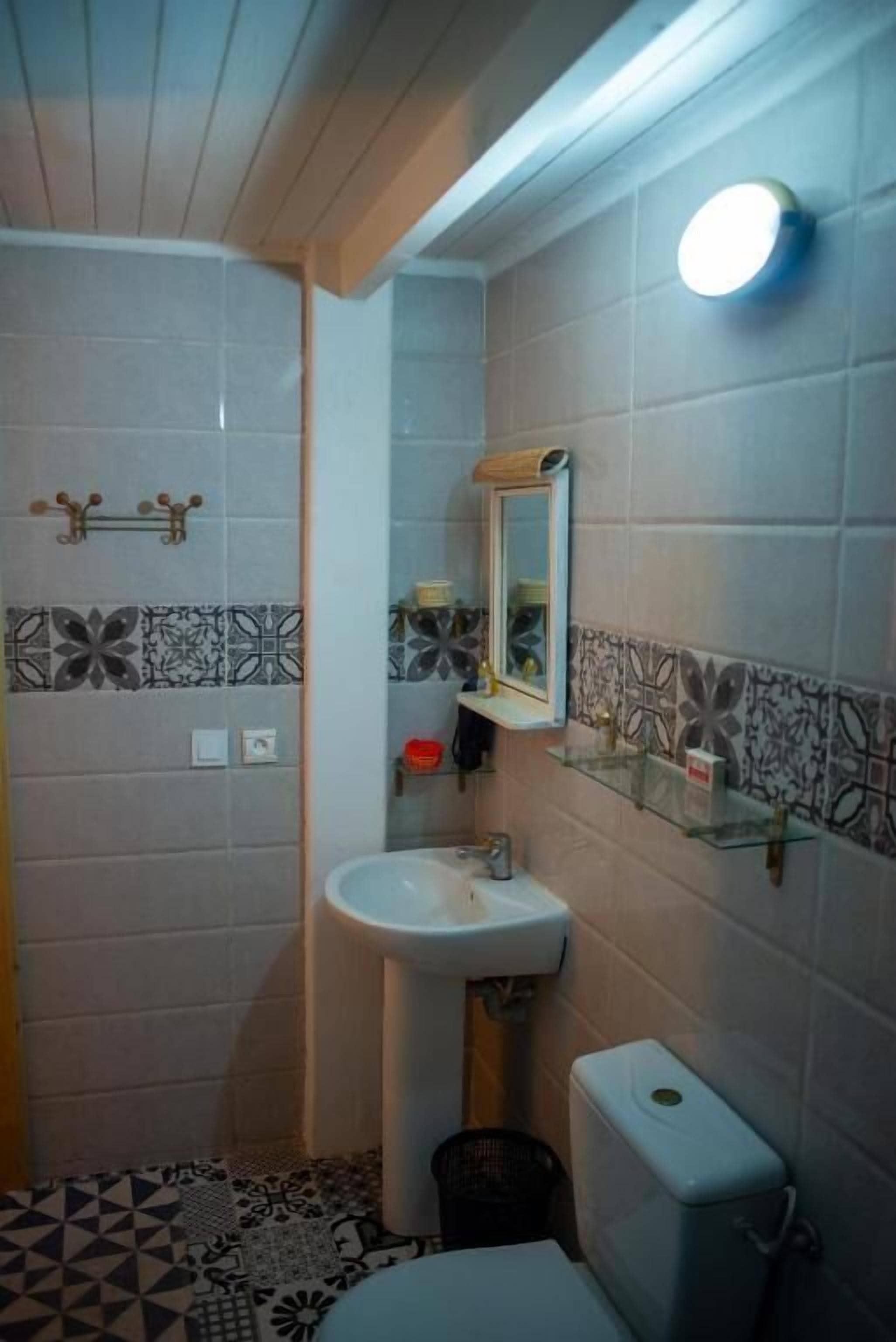 A bathroom with a toilet, sink, and mirror.