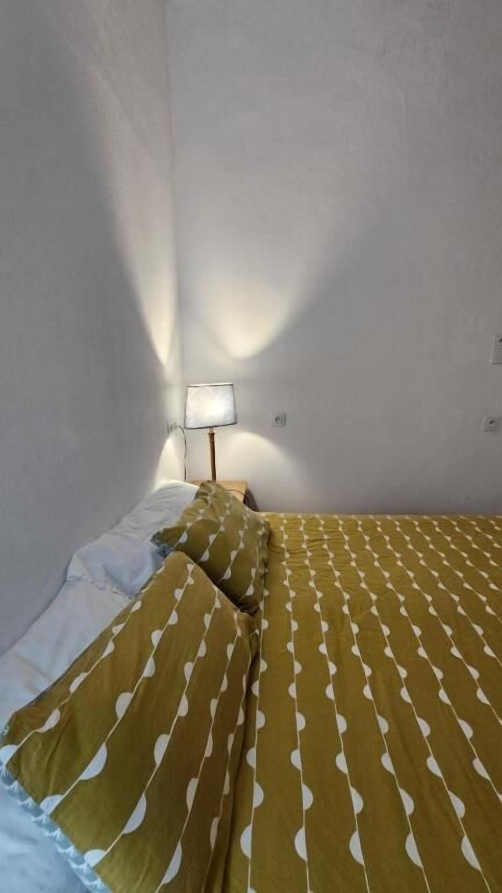 A bedroom with a bed, pillows, and a bedside lamp.