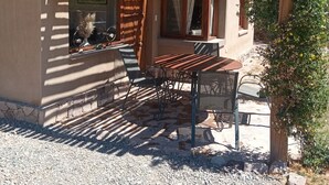 Un espacio de estar al aire libre rústico con una mesa, sillas, una pérgola y vistas a un paisaje montañoso.