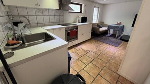 Une cuisine compacte équipée d’un évier, d’une cuisinière et d’un four à micro-ondes. On y trouve également un petit coin repas avec une table et un canapé.