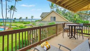 Un balcon donnant sur une piscine et des palmiers, une clôture en bois et une maison en arrière-plan.