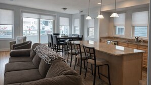 A modern kitchen with a central island, dining area with chairs, and a sofa. - Located in the heart of Ocean City,Downtown this spacious 4-bedroom apartment. (Ocean City)