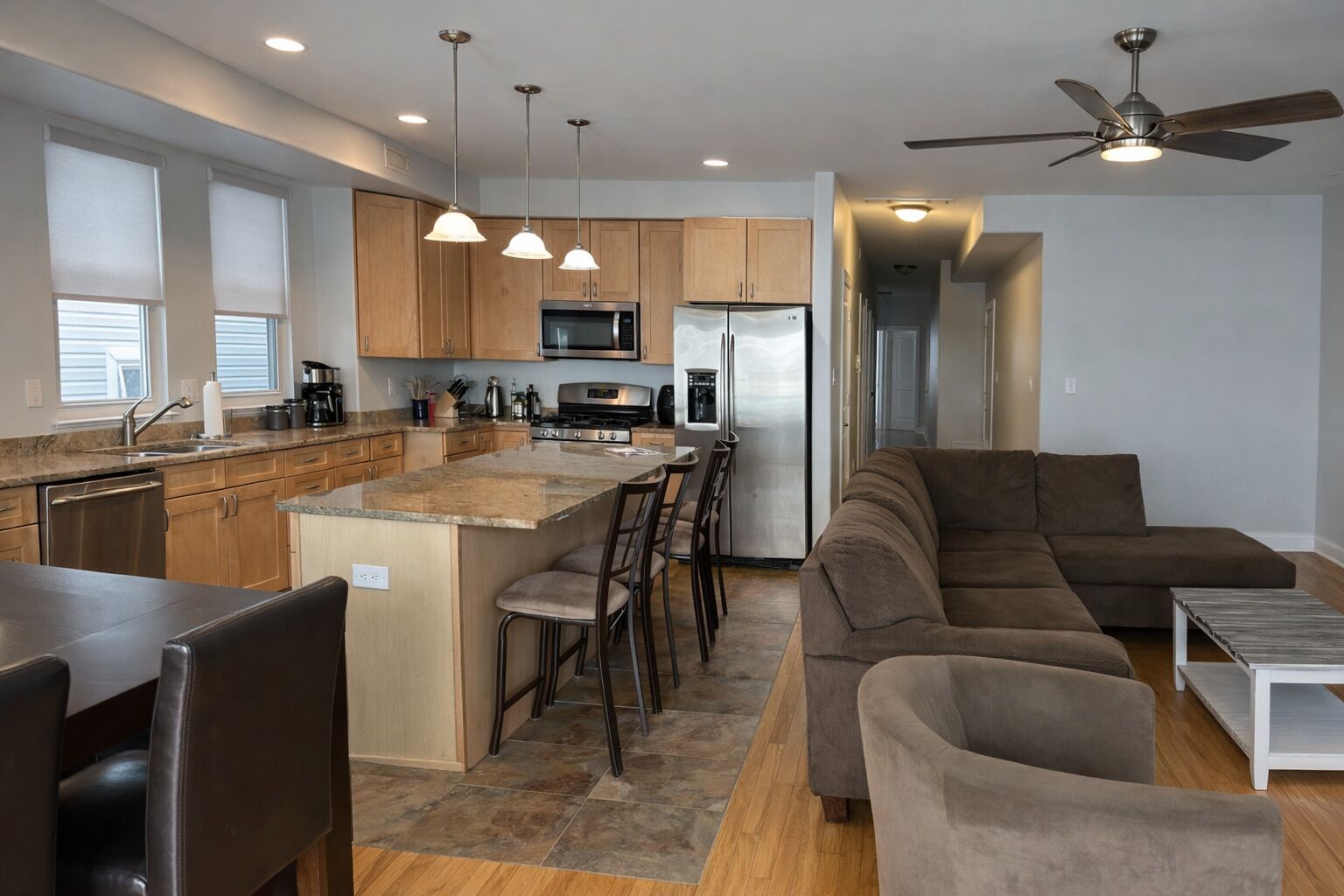 A modern kitchen with a central island, stainless steel appliances, and pendant lighting.