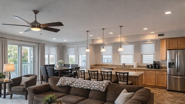 A modern living room with a sofa, a dining table, and a kitchen area with a refrigerator and pendant lights. - Located in the heart of Ocean City,Downtown this spacious 4-bedroom apartment. (Ocean City)