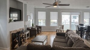 A spacious living room with a large sectional sofa, a fireplace, a television, and a ceiling fan. - Located in the heart of Ocean City,Downtown this spacious 4-bedroom apartment. (Ocean City)