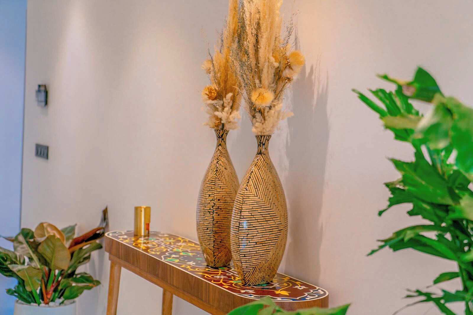 Two decorative vases with a geometric pattern on a wooden table against a plain wall.