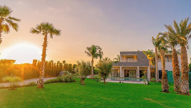 A modern two-story house with a swimming pool, surrounded by palm trees and a well-maintained lawn. - Villa Lumeria (Marrakech)