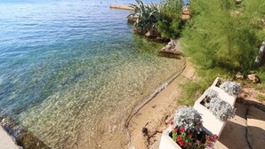 Um lago translúcido com uma praia arenosa, um píer e vegetação.