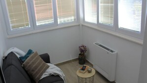 Uma sala de estar moderna com um sofá escuro, uma mesa de centro redonda e um radiador.