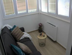 Ein modernes Wohnzimmer mit einem dunklen Sofa, einem runden Couchtisch und einer Heizung.